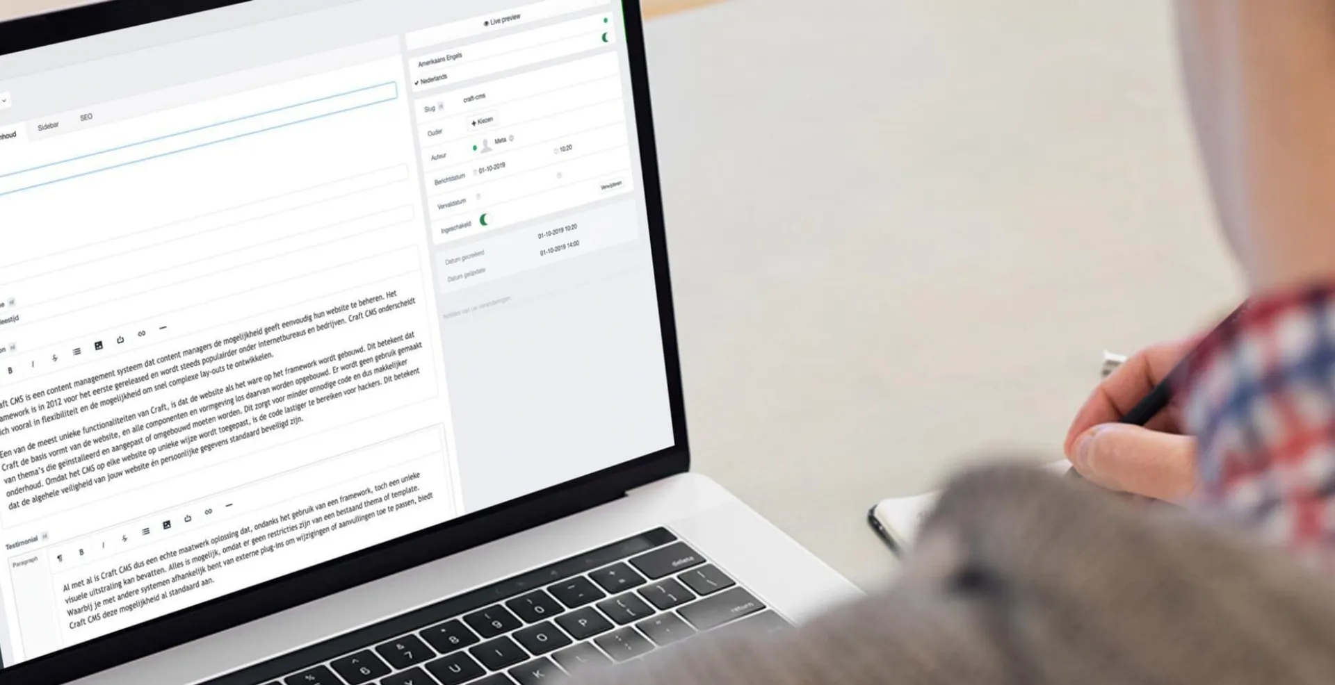 A person taking notes beside a laptop showing the Craft CMS editor
